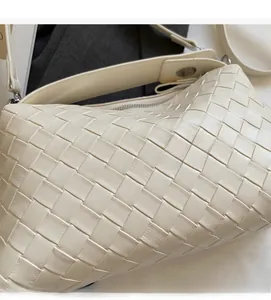 Vue détaillée du sac à bandoulière tressé crème avec large sangle et boucles argentées