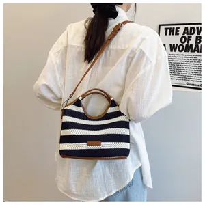 Close-up of blue and white striped woven tote bag with brown leather handles and logo