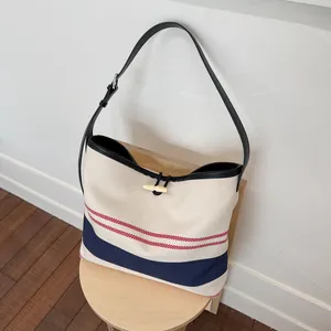 Detail view of nautical striped canvas tote bag with black leather strap and toggle closure