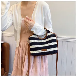 Detailed close-up of navy striped knit tote bag with brown leather handles and straps