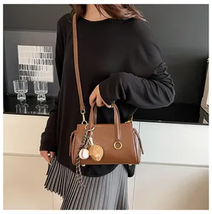 Detailed shot of brown PU handbag with gold ring hardware and baseball glove keychain