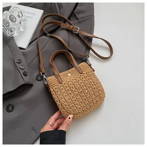 Gros plan sur la texture en paille tressée et les poignées en cuir marron du sac