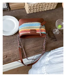 Detail einer bunten gewebten Beuteltasche mit braunem Lederbesatz und Kettenriemen