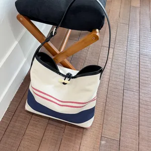 Detailed view of casual striped canvas tote bag with toggle closure on a wooden stool