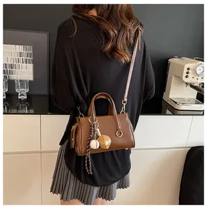 Brown leather handbag with baseball glove charms shown in a cozy lifestyle setting