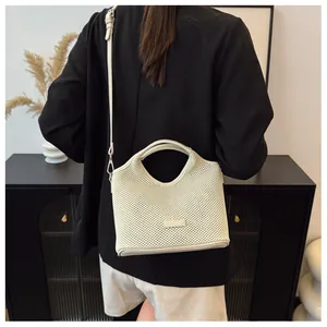 Detail view of white perforated tote bag with brand logo and detachable shoulder strap