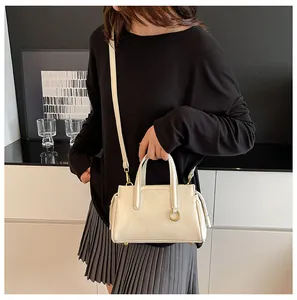 Detail view of cream white minimalist handbag with gold ring and reinforced handles