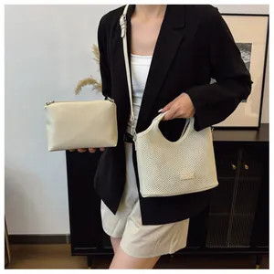 Detail of a chic cream white cutout tote bag with matching inner pouch and slim strap