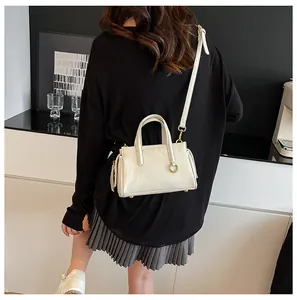 Back view of model wearing cream crossbody bag with golden hardware and leather strap