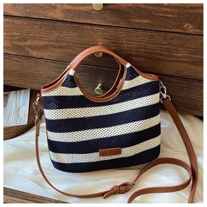 Detail of navy stripe knit tote with brown leather handles and brand logo patch