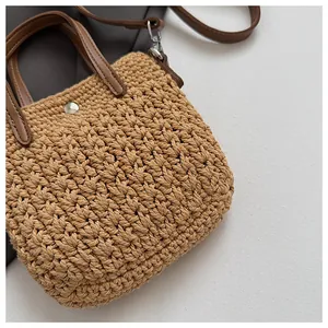 Vue détaillée du sac à main tissé kaki montrant la texture tressée et l'anse en cuir brun