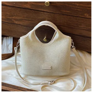 Detail of cream woven tote bag with circular handle and brand patch on silk surface
