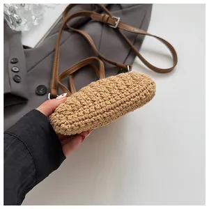 Détail du sac en paille tissée avec des brides en cuir marron et une base arrondie