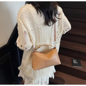 Détails de la texture tissée kaki et des ferrures argentées du sac à bandoulière