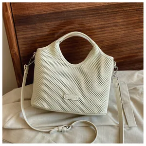 Macro detail of cream woven tote bag showing fine knit texture and leather brand plaque