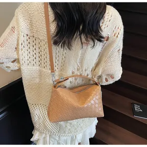 Gros plan d'un sac à bandoulière en cuir tressé caramel avec bandoulière réglable et boucle