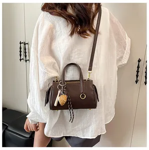 Detail of dark brown faux leather crossbody bag with charms on model from back view