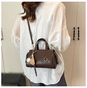Deep brown crossbody bag with baseball charm shown on model in a modern room setting