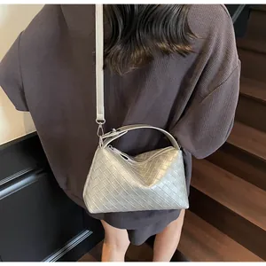 Détail d'un sac argenté tissé montrant sa texture métallique et sa bandoulière réglable