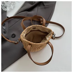 Détail du sac seau tissé avec poignées en cuir marron et fermeture à bouton magnétique