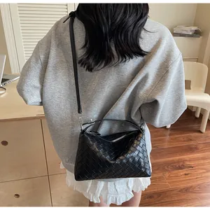 Détail d'un sac hobo en cuir tressé noir avec fermeture éclair et bandoulière fine
