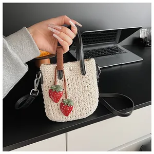 Détail du sac cabas en coton tissé avec poignées en cuir noir et breloques fraises