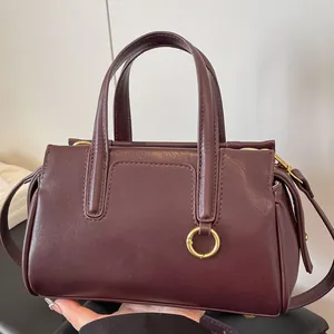 Deep red burgundy leather handbag with dual handles and elegant golden ring buckle