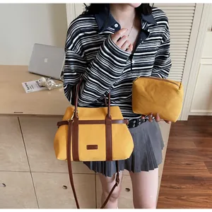 Dettaglio della borsa tote in tela gialla e pochette con cinturini in pelle e ganci in metallo