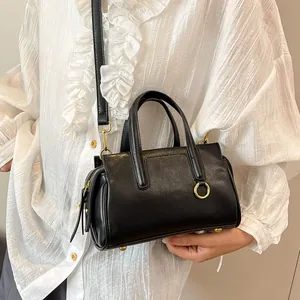 Classic black handbag with gold hardware and shoulder strap worn by a model in a white shirt