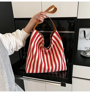 Detail of red and white striped canvas tote bag with brown faux leather handles