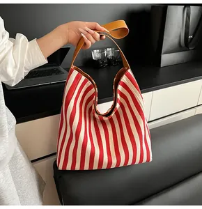 Detail of red and white striped canvas tote bag with brown leather shoulder strap
