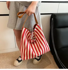 Detail of red and white striped canvas tote with brown leather straps on a model