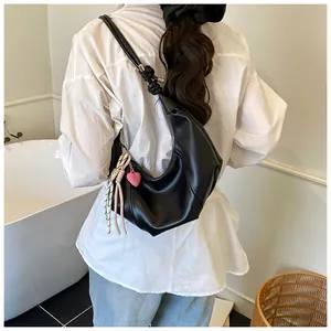 Détail du sac hobo noir avec bandoulière nouée et breloque cœur porté par un mannequin