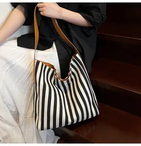 Detail of striped canvas tote bag with brown leather shoulder straps and large interior