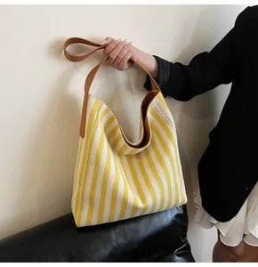 Macro detail of yellow and white striped woven canvas tote bag with brown leather handle