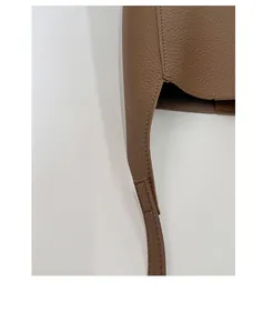 Détail du cuir à grain litchi et des coutures fines sur un sac à bandoulière marron