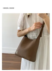 Sac seau marron avec logo D argenté porté sur une robe vintage rayée chic