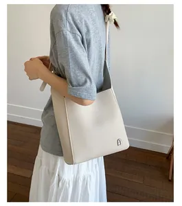 Détail du sac à bandoulière en cuir blanc cassé avec breloque cadenas sur un mannequin