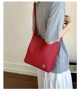 Gros plan d'un sac cabas rouge en cuir texturé litchi avec détail du logo fer à cheval
