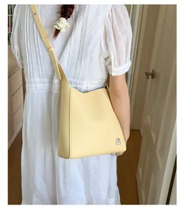 Détail d'un sac seau en cuir grainé jaune clair avec logo en métal argenté élégant