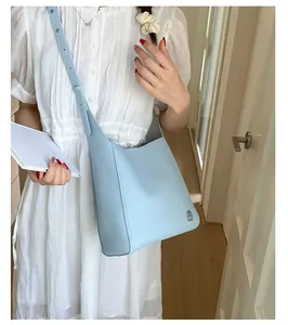 Détail du sac à bandoulière en cuir bleu clair à texture litchi et logo argenté