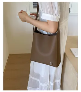 Vue macro d'un sac seau en cuir grainé marron avec une boucle en métal en forme de D emblématique