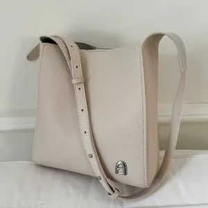 Sac hobo élégant en cuir grainé beige avec logo métallique argenté et bandoulière