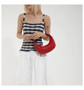 Détail du sac demi-lune rouge foncé avec coutures géométriques et boucle en métal poli