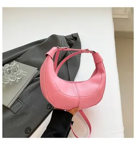 Détail du sac demi-lune rose avec cuir grainé litchi et poignée à gros nœud