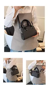 Détail d'un sac à main noir en forme de coquille avec texture matelassée et métal argent