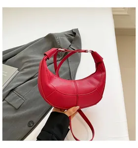 Gros plan sur un sac croissant rouge vif en cuir grainé avec coutures décoratives