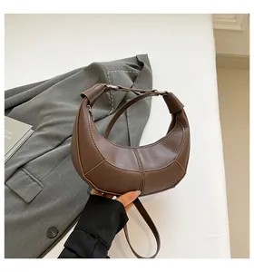Détail du sac selle demi-lune marron avec ferrures argentées et texture en cuir