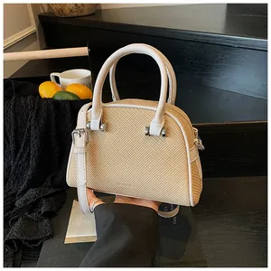Détail d'un sac tressé beige avec bordure en cuir blanc et boucles en métal argenté