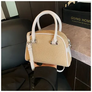 Détails de la texture tissée beige et des poignées en cuir blanc de ce petit sac Boston